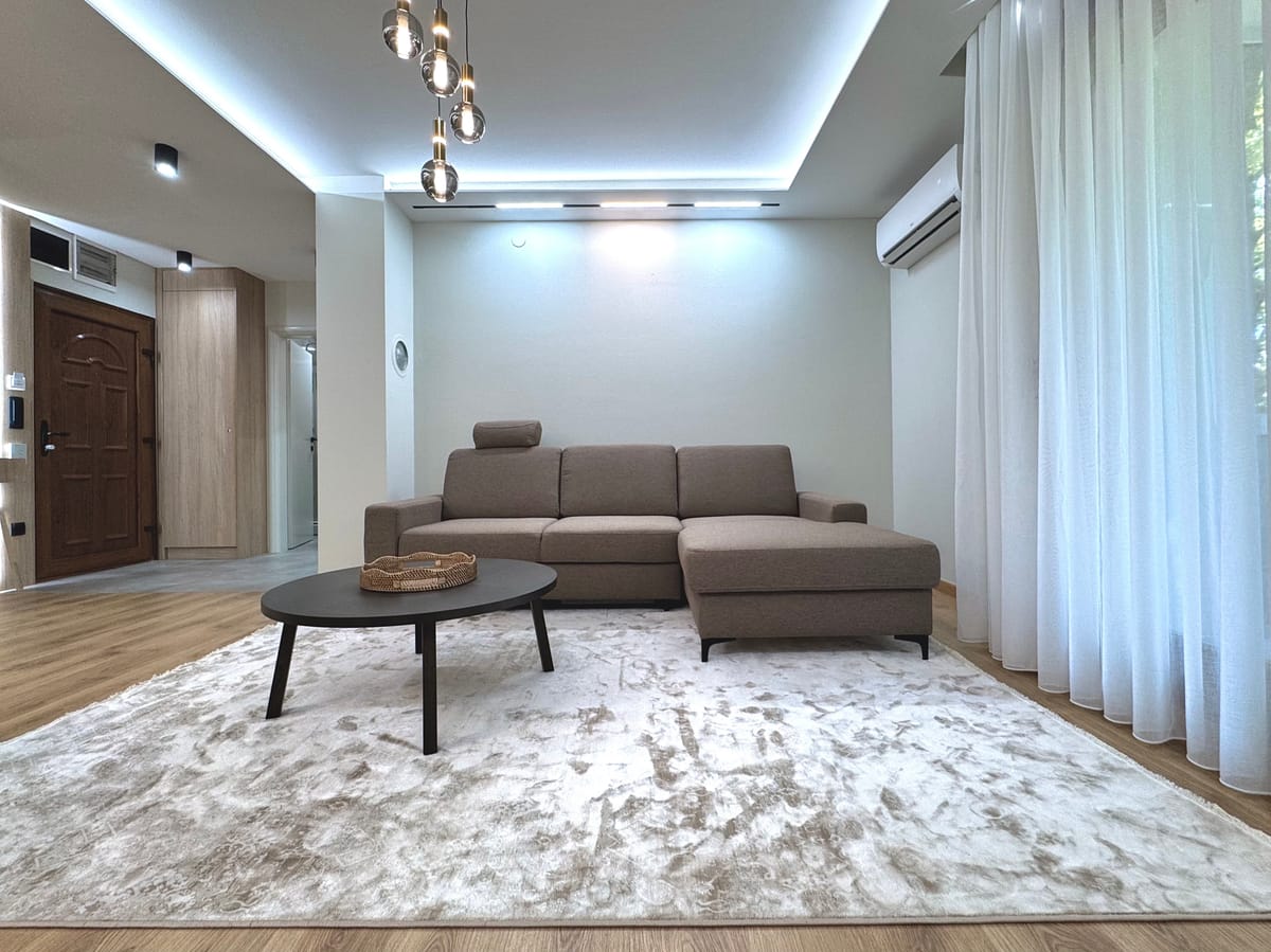 Wohnzimmer mit Ecksofa, Teppich und Flur zum Eingang