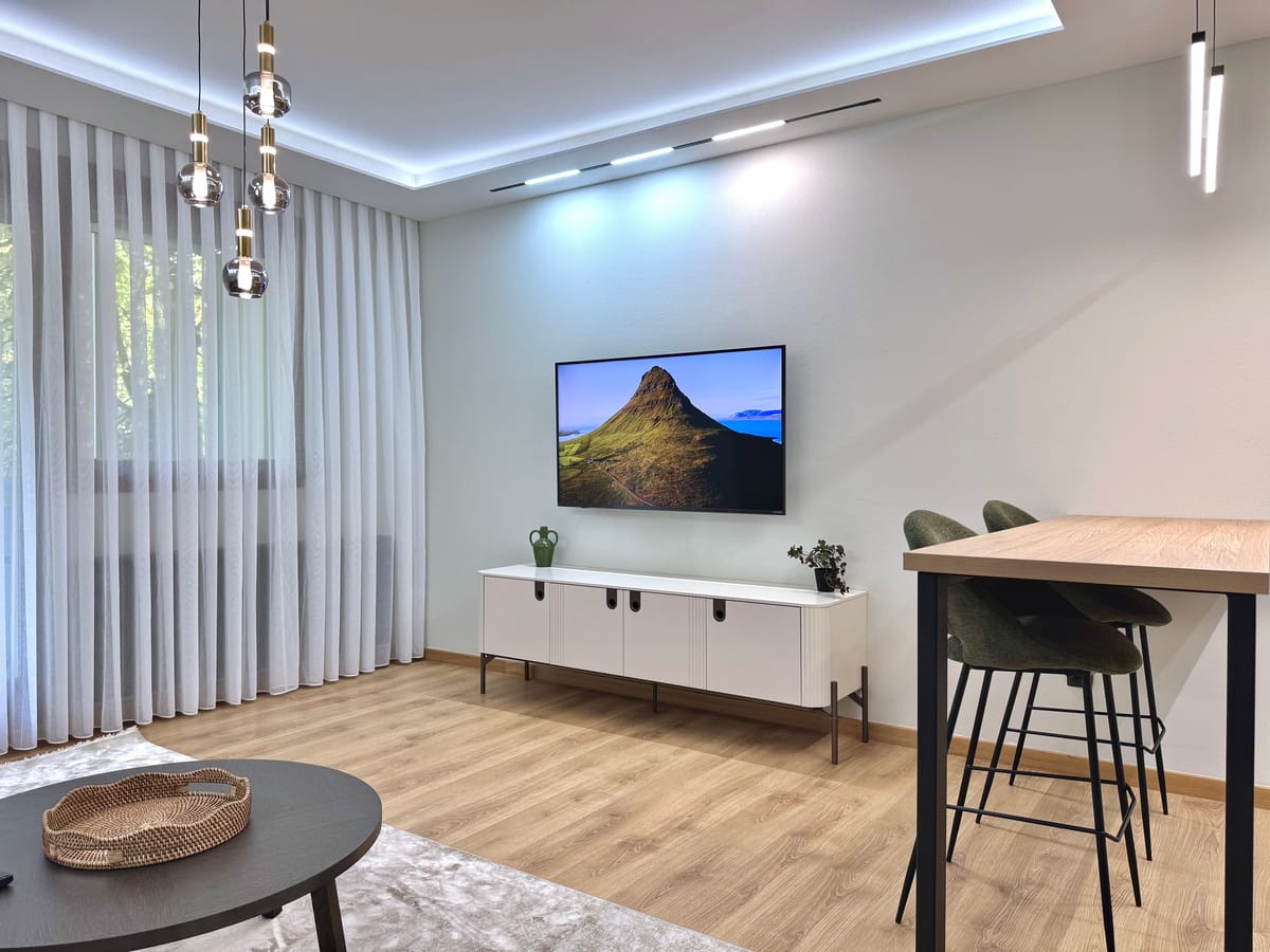 Smart-TV und Sideboard im Wohnzimmer, neben dem hohen Bartisch